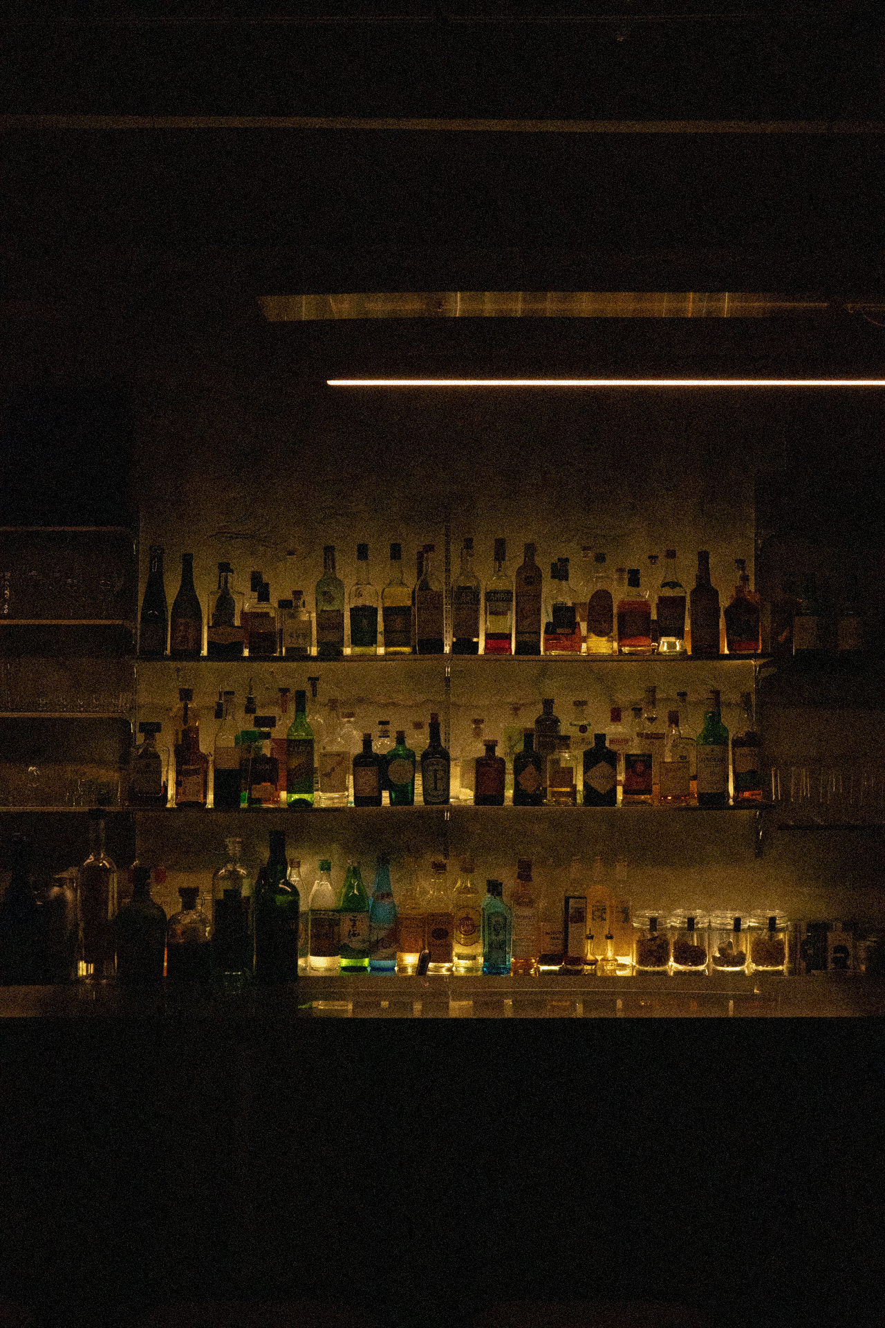 Spirit bottles lined along the lit shelves of the back bar.